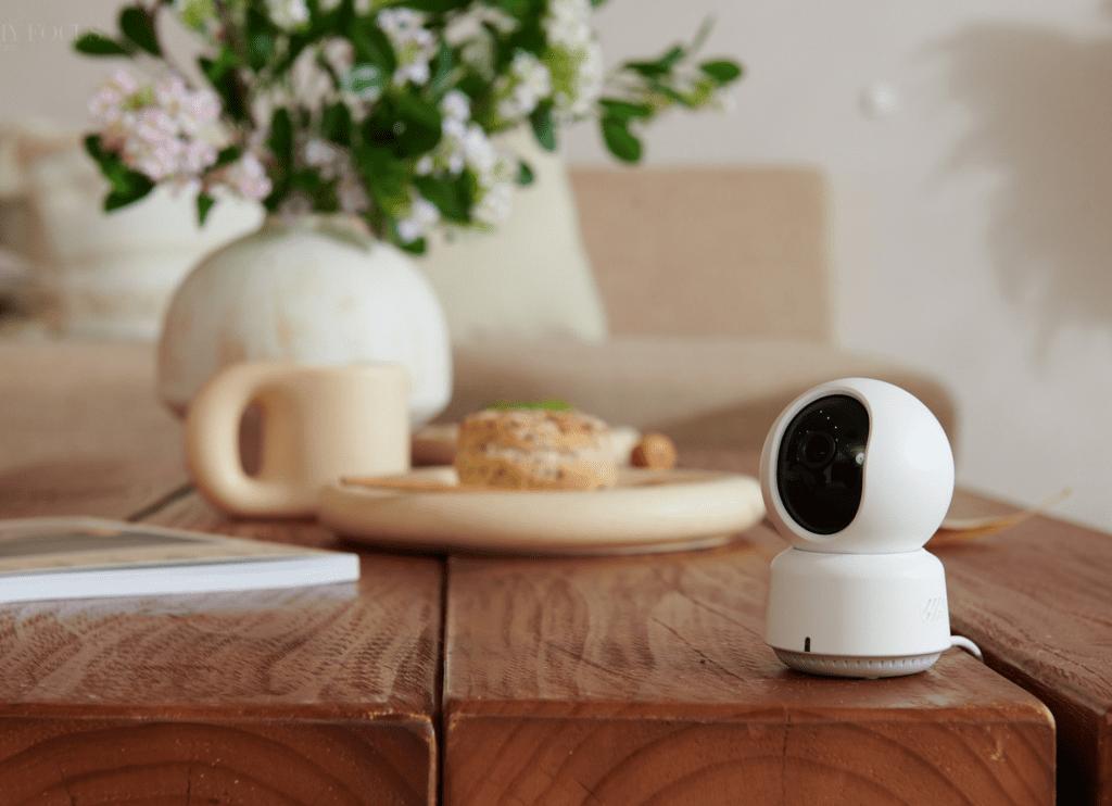 Aqara smart kamera – spoľahlivé monitorovanie domácnosti so vzdialeným prístupom Inteligentná bezpečnostná kamera Aqara umiestnená na drevenom stole v modernej obývačke, monitorujúca priestor pre väčšiu bezpečnosť.